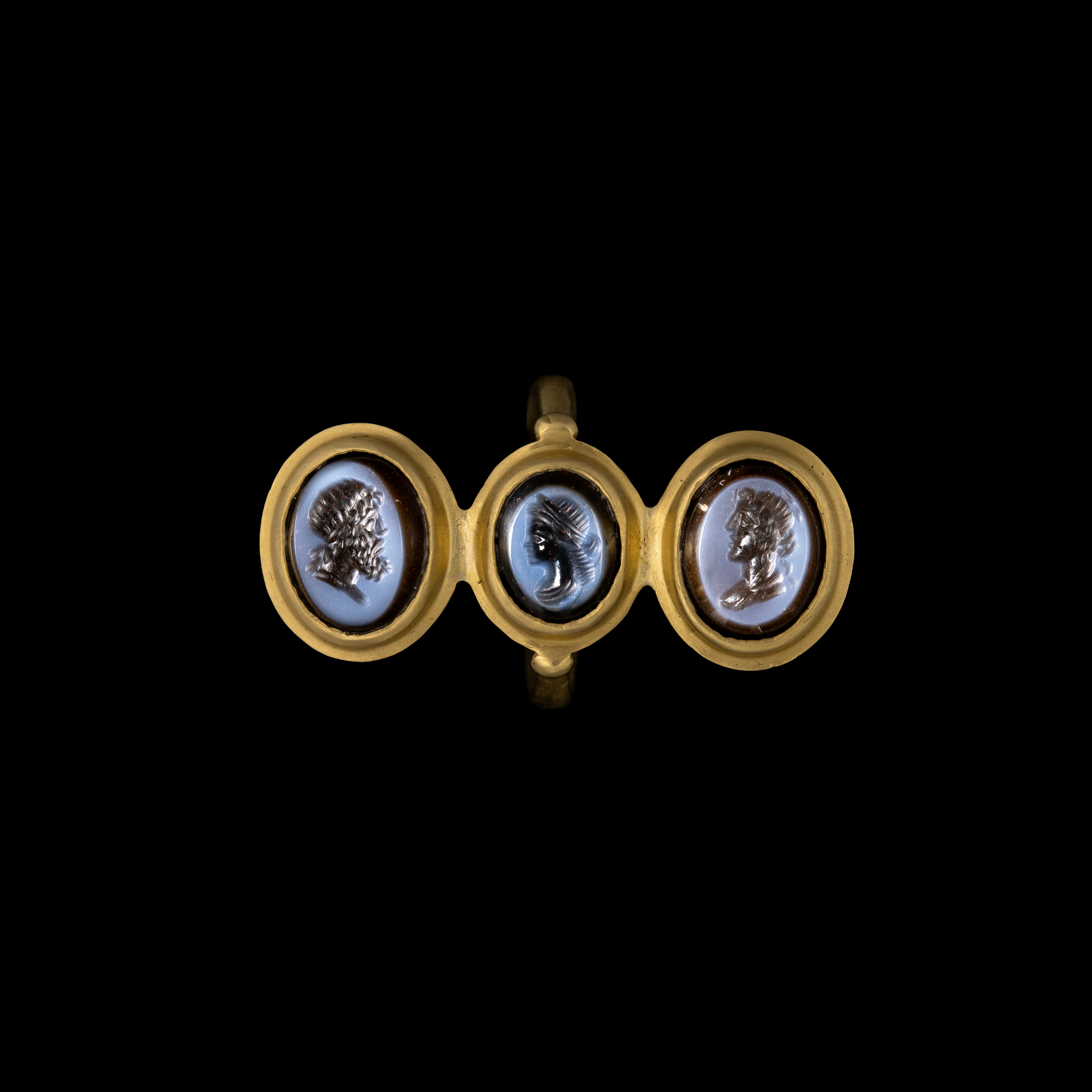 A modern gold ring set with three nicolo intaglios. Classical busts.
